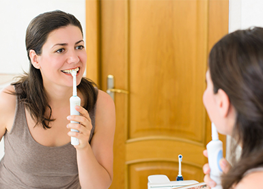 Woman Brushing Teeth with Electric Toothbrush